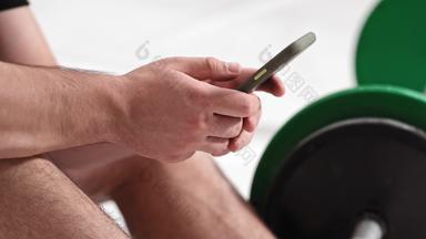 打破年轻的男人。坐着地板上黑色的绿色语气健身杠铃设备重量培训概念男性体育设备培训健康的生活方式概念镜头